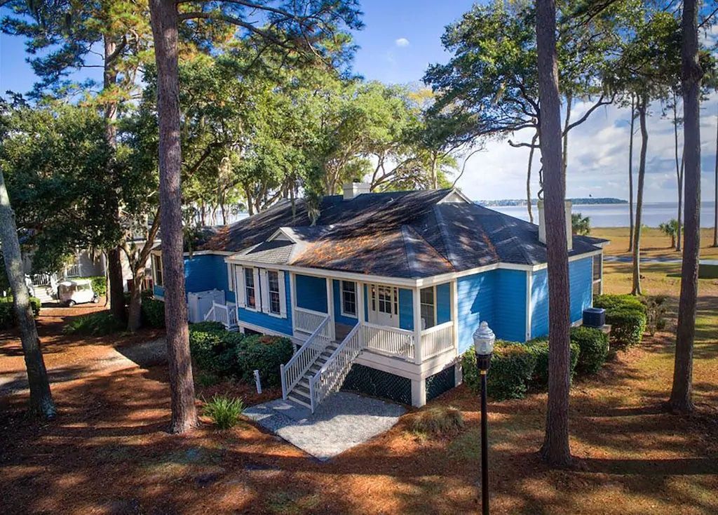 An aerial view of a blue and white house surrounded by trees.
