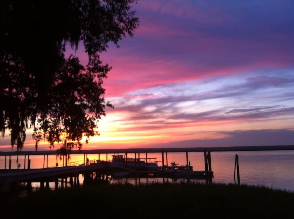 A sunset over a body of water with a dock in the foreground