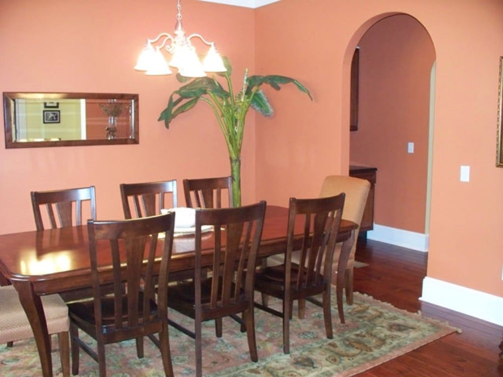 A dining room with a table and chairs and orange walls