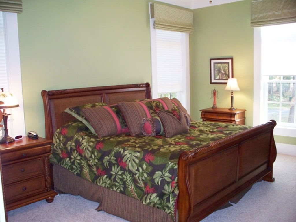 A bedroom with green walls and a sleigh bed