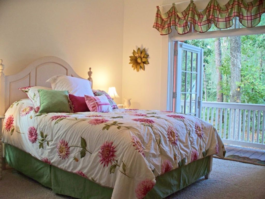 A bed with a floral comforter is in a bedroom with a balcony.