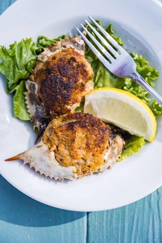 A white plate topped with crab cakes and lettuce with a fork.