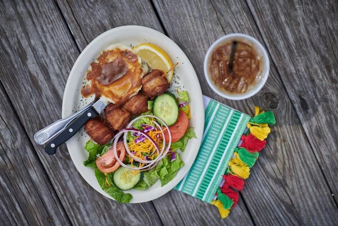 A plate of food with a salad and beans on a wooden table.