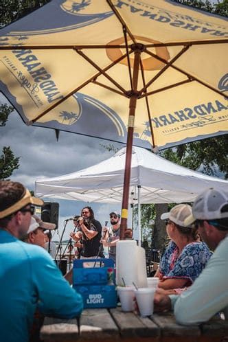 A group of people are sitting at a table under an umbrella.