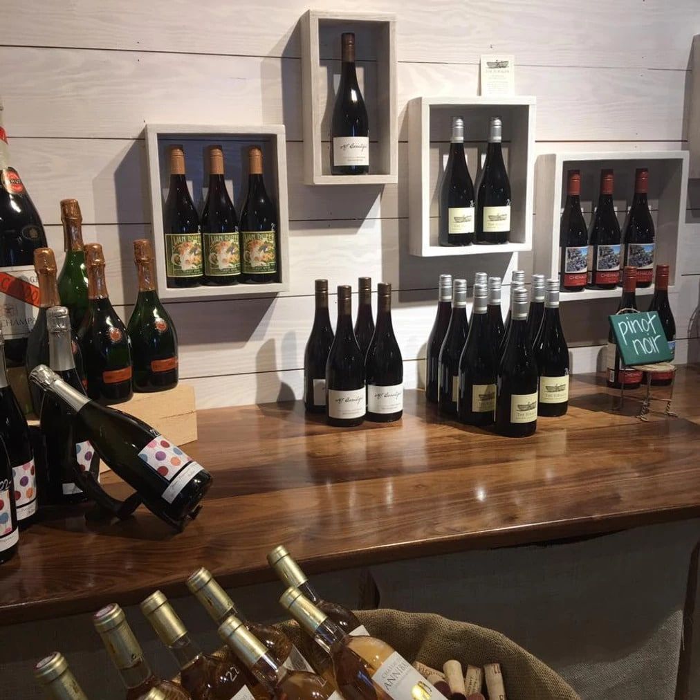 Many bottles of wine are on display on a wooden table