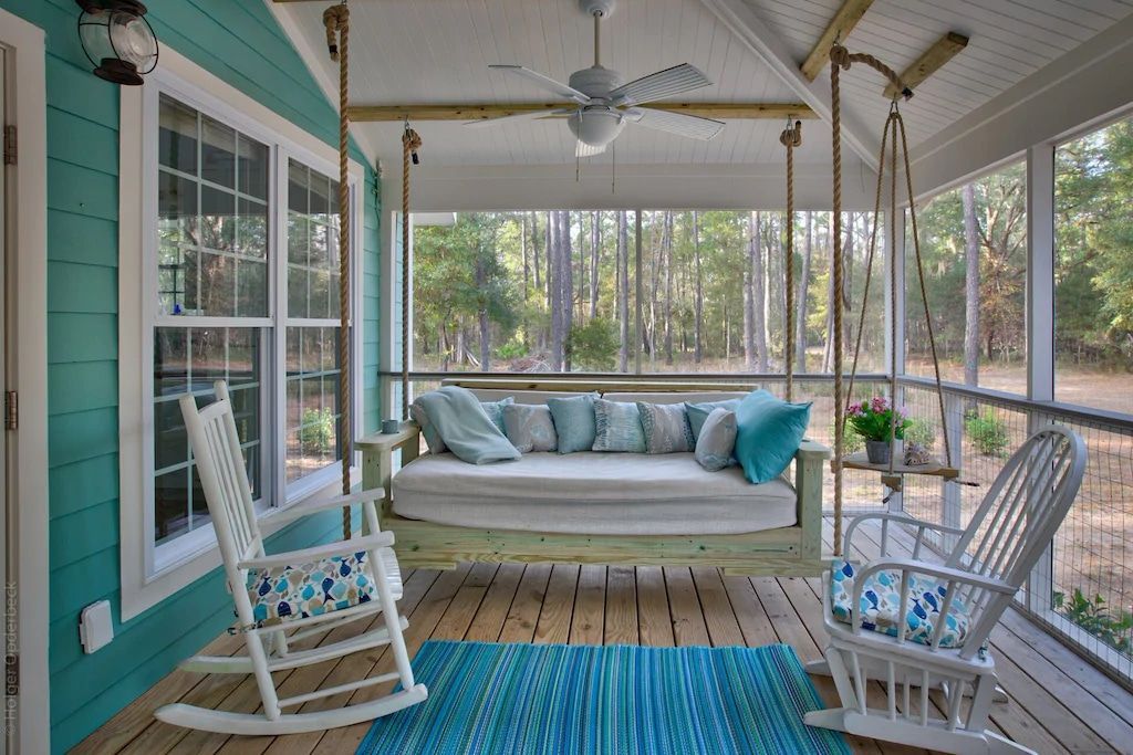 A screened in porch with a swing and rocking chairs.