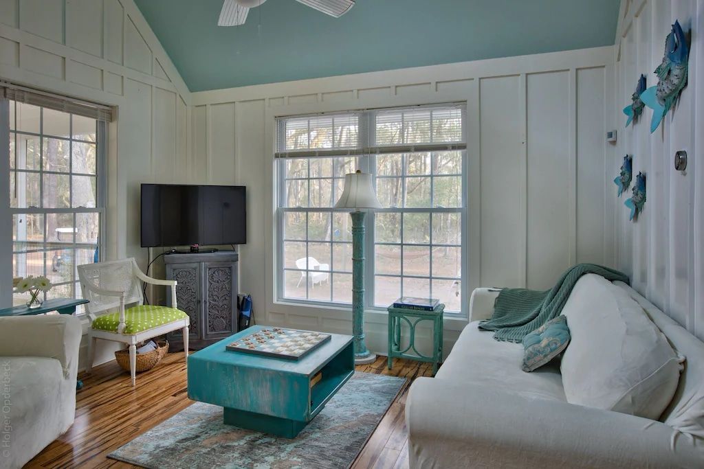 A living room with a couch , chairs , coffee table and television.