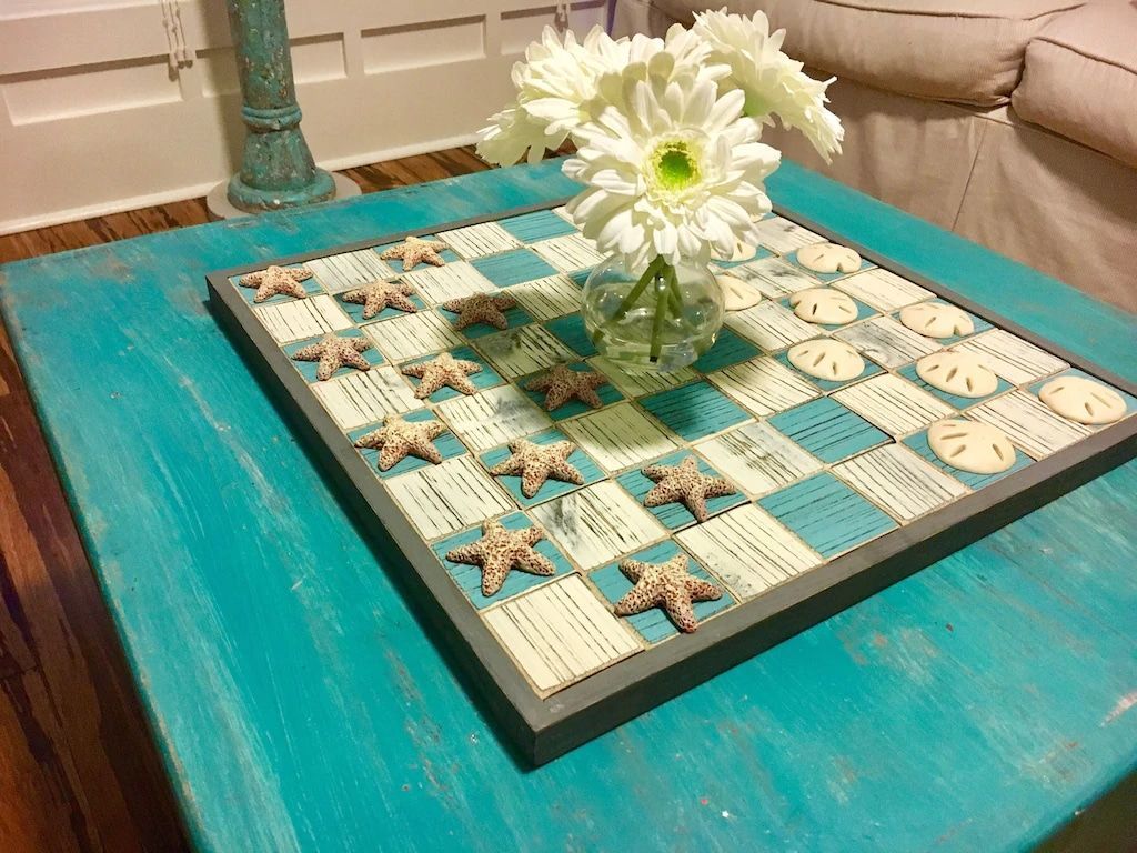 A blue table with a chess board and a vase of flowers on it.
