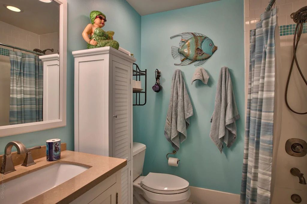 A bathroom with a toilet , sink , mirror and shower curtain.