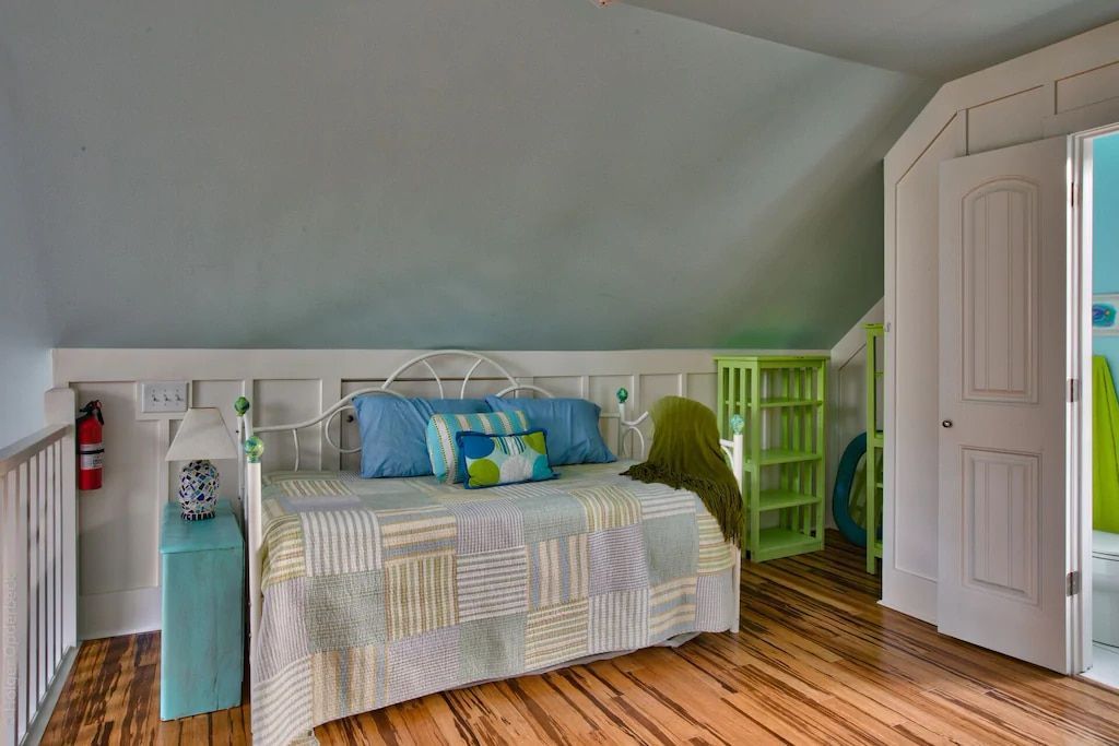 A bedroom with a day bed and a wooden floor.