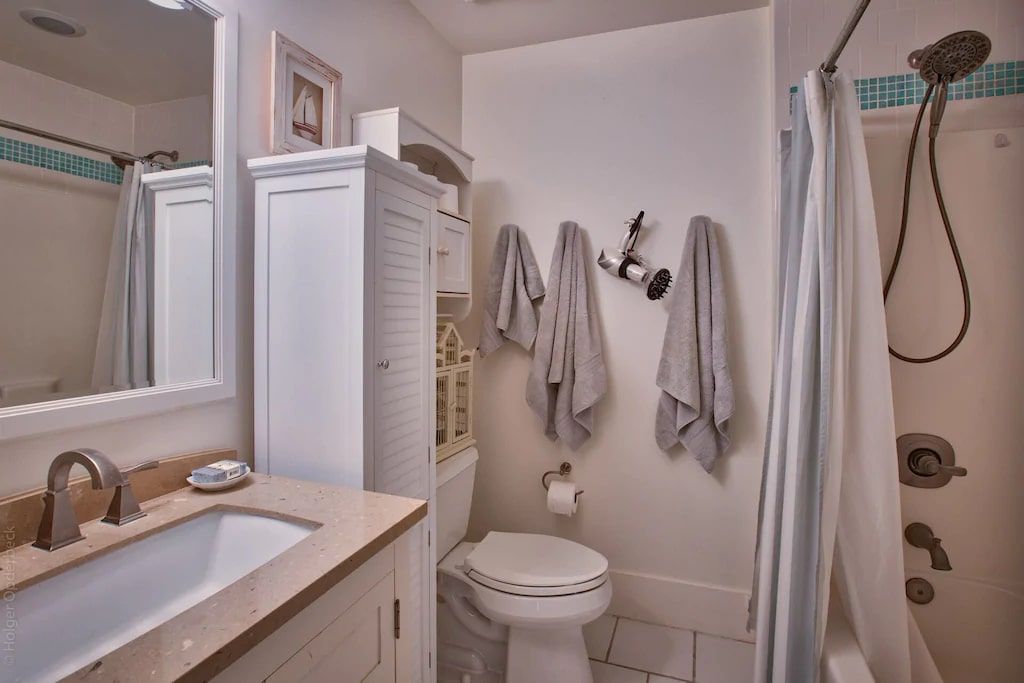 A bathroom with a toilet , sink , mirror and shower.