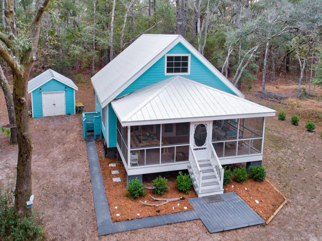 An aerial view of a blue and white house with a screened in porch.