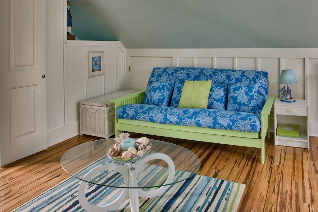 A living room with a blue couch and a glass coffee table