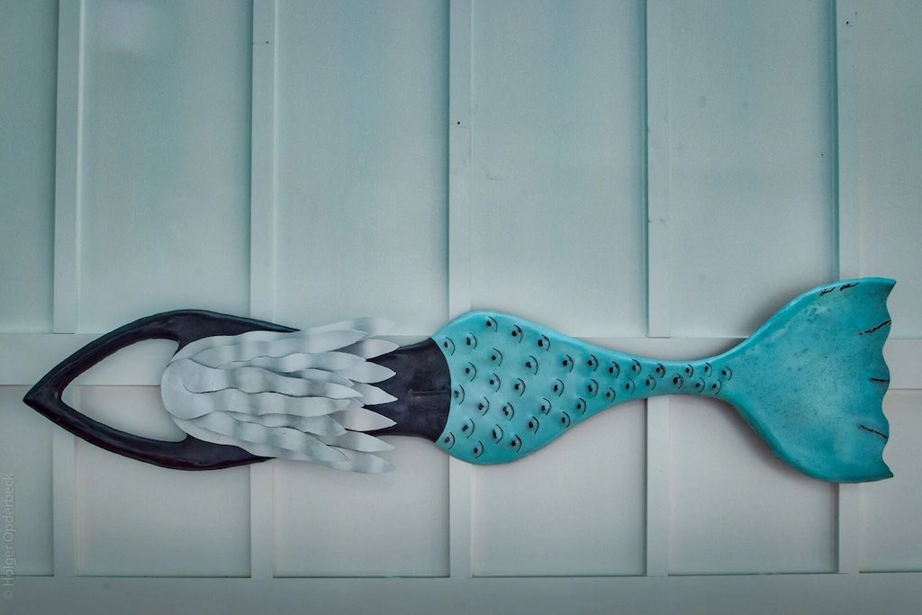 A mermaid tail is hanging on a white wall.