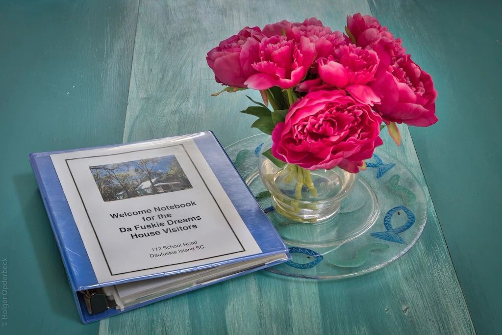 A vase of pink flowers sits next to a blue binder