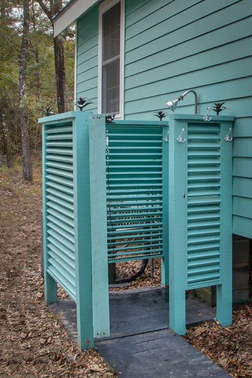 A blue house with a walkway leading to a outdoor shower.