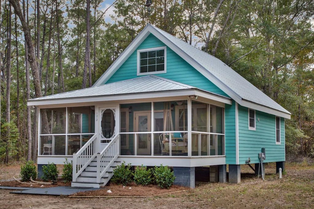 A blue house with a screened in porch and stairs