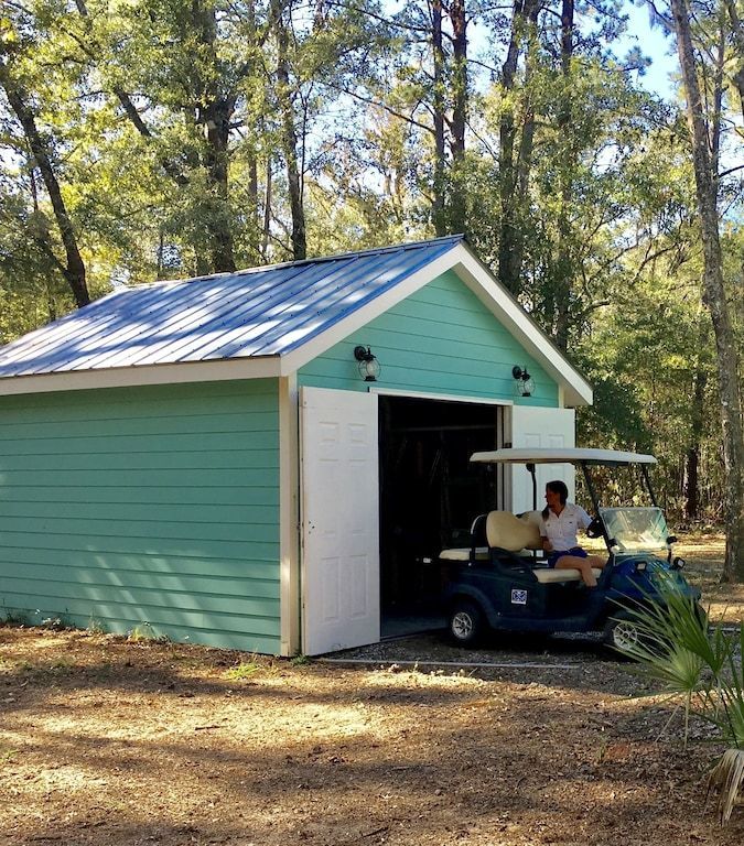 A golf cart is parked in front of a green garage