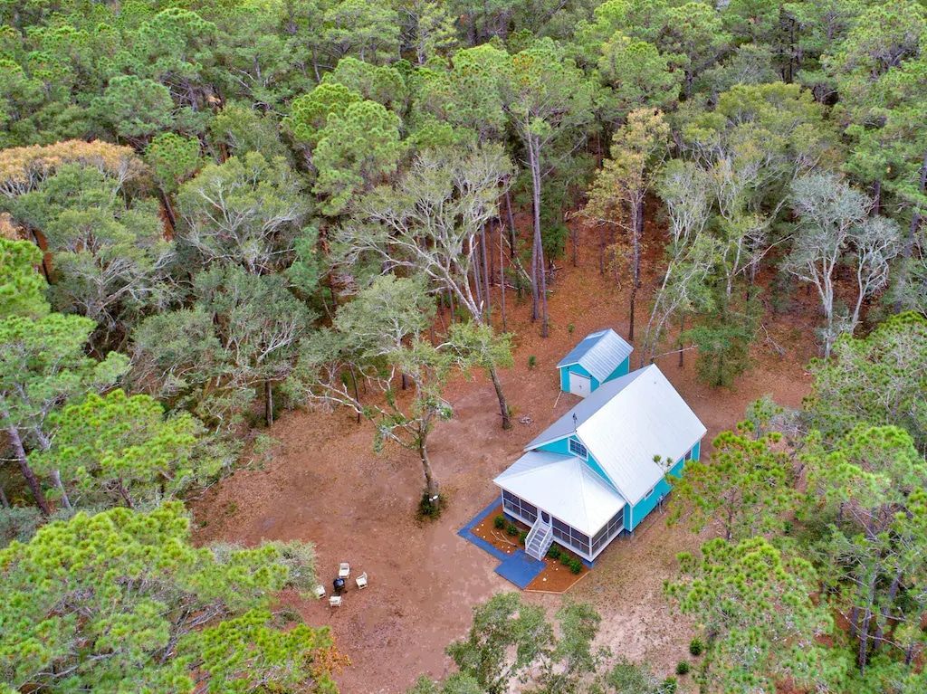 An aerial view of a house in the middle of a forest.