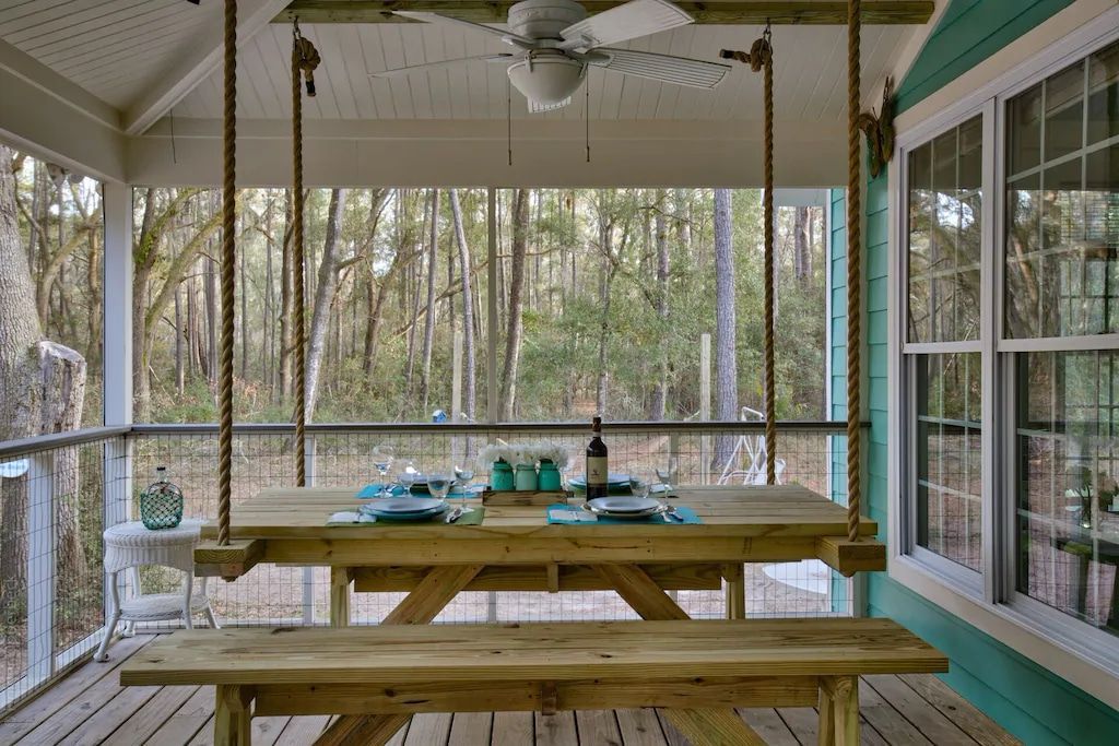 A screened in porch with a picnic table and benches