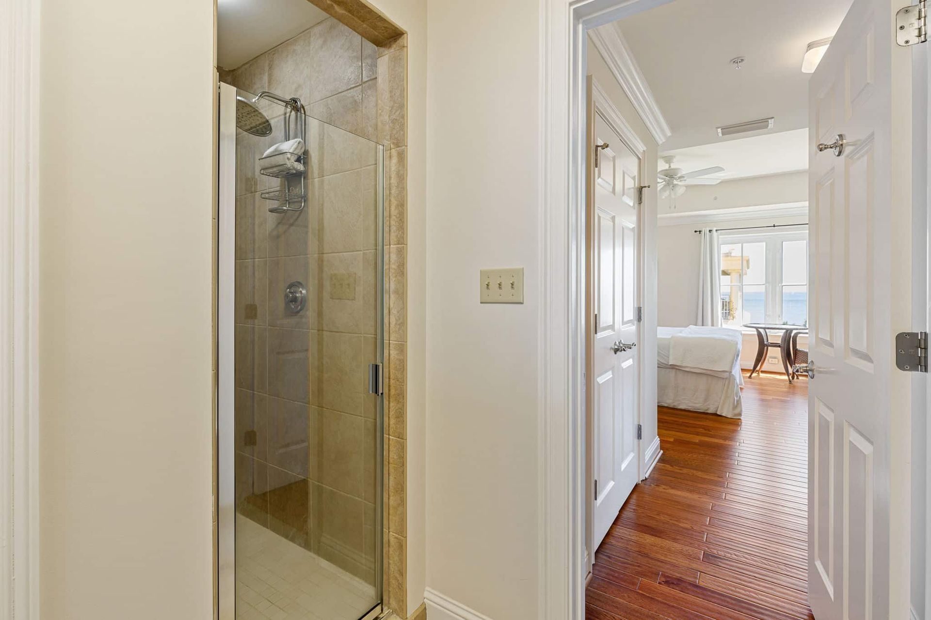 A hallway leading to a bedroom with a walk in shower.