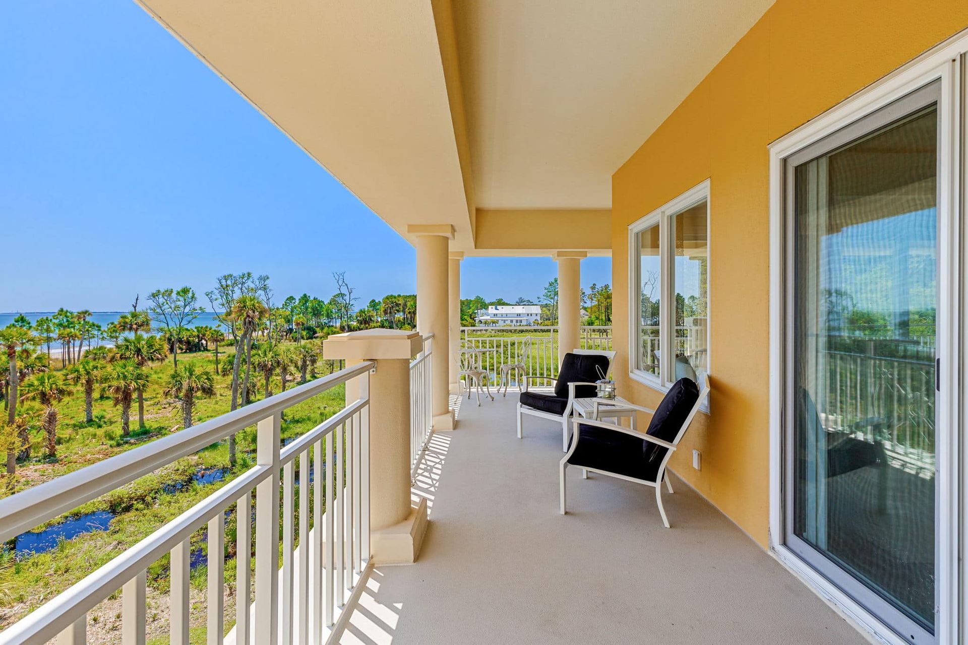 A balcony with a view of the ocean and palm trees