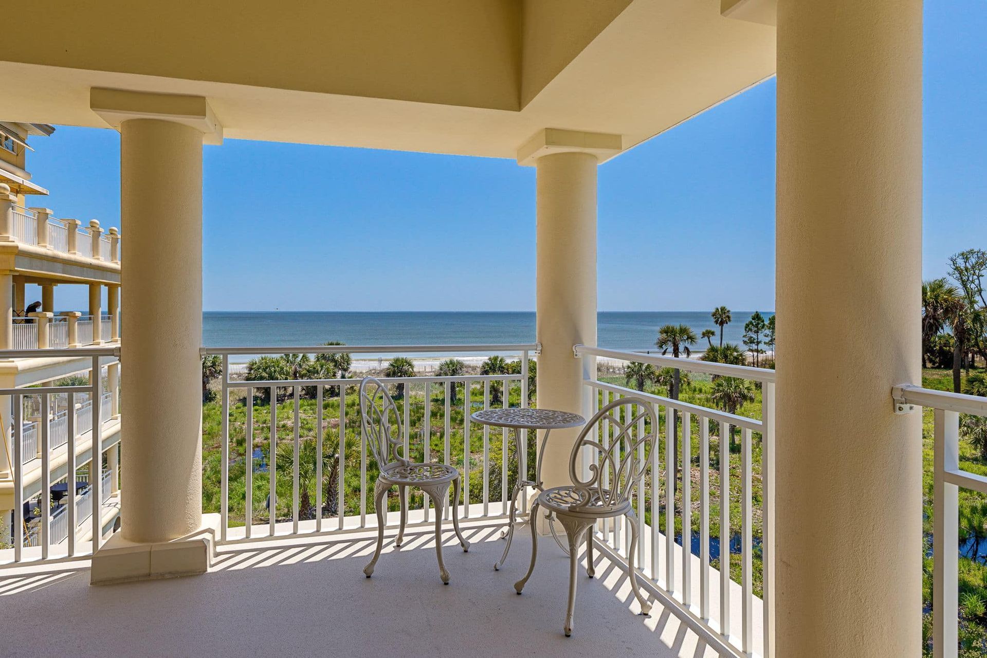 A balcony with a table and chairs overlooking the ocean