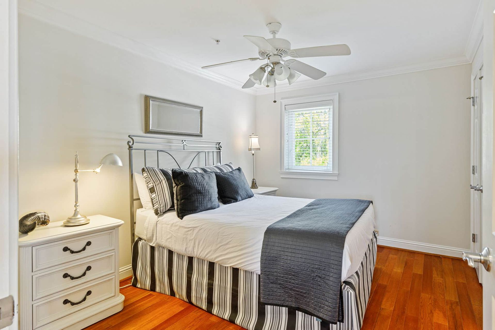 A bedroom with a bed , nightstand , dresser and ceiling fan.