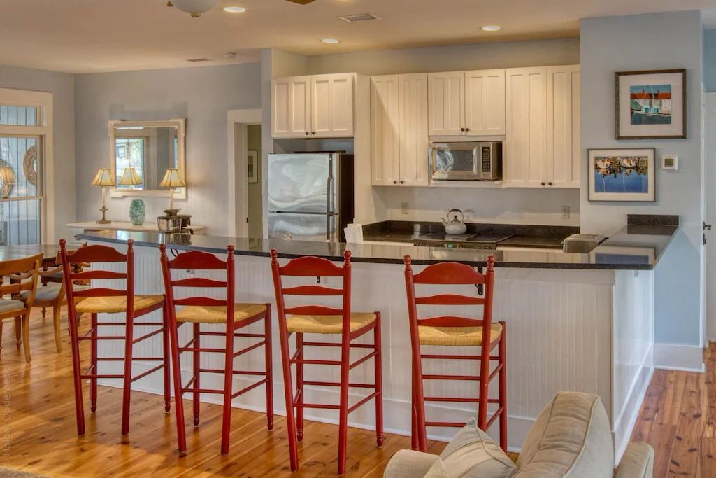 A kitchen with white cabinets and red chairs