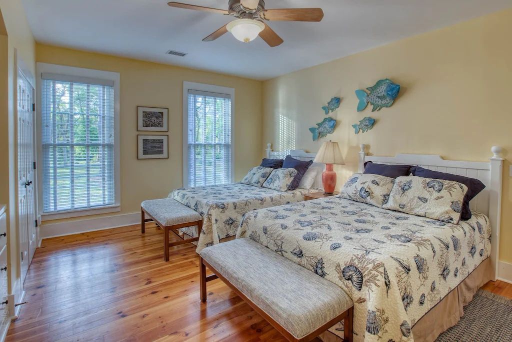 A bedroom with two beds and a ceiling fan.