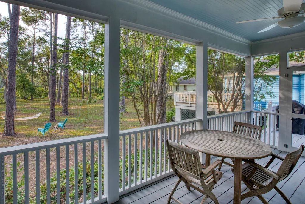 A porch with a table and chairs and a ceiling fan.