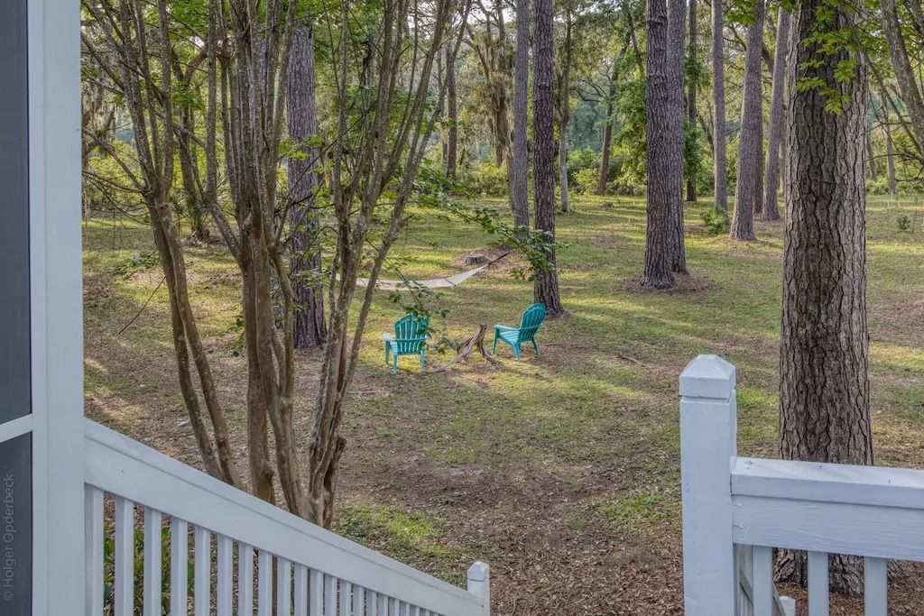 There are two blue chairs in the middle of the woods.