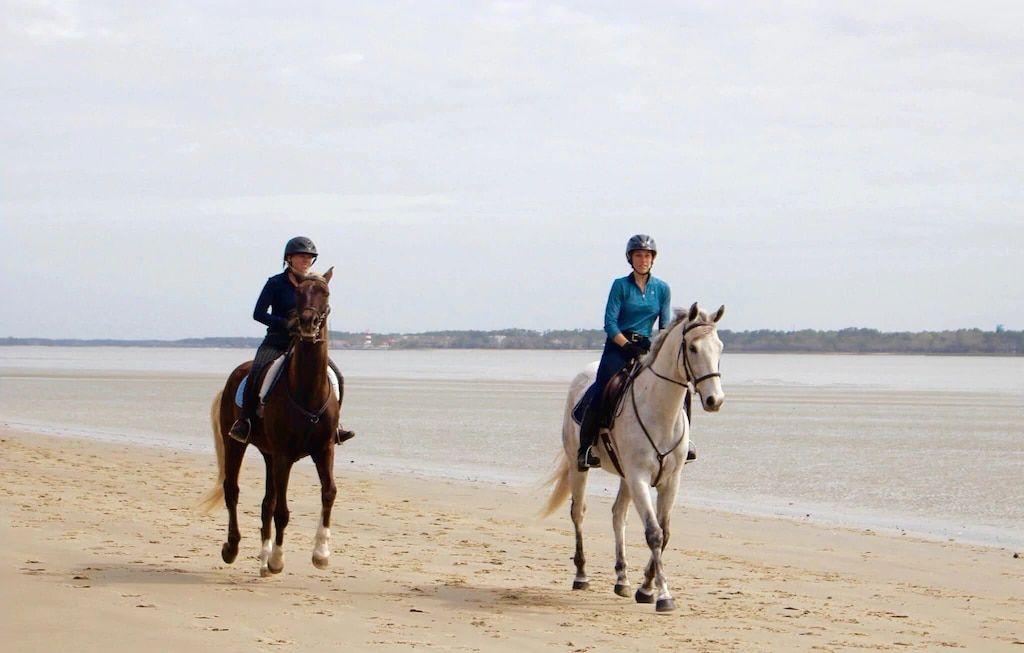 Two people are riding horses on the beach.