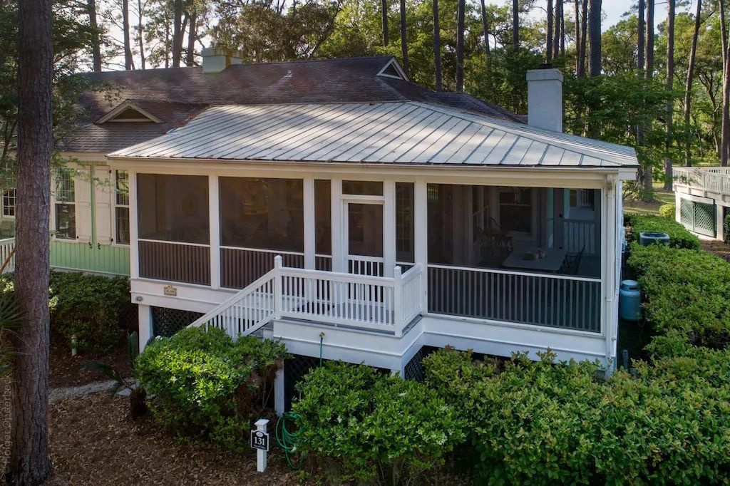 An aerial view of a house with a screened in porch surrounded by trees.