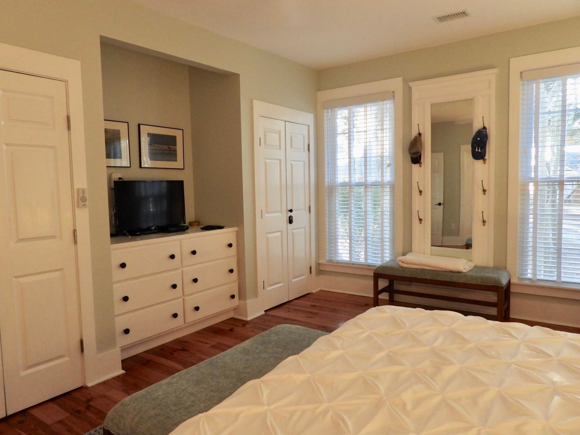 A bedroom with a bed , dresser , television and mirror.