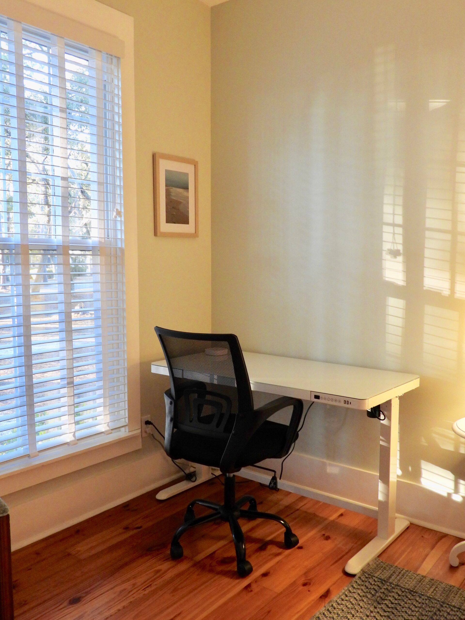 A room with a desk and chair and a window with blinds