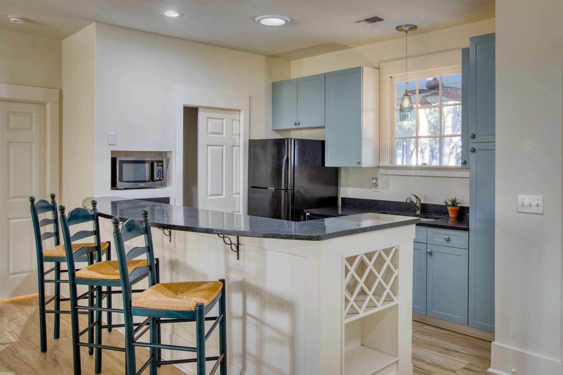 A kitchen with blue cabinets and stools and a large island.