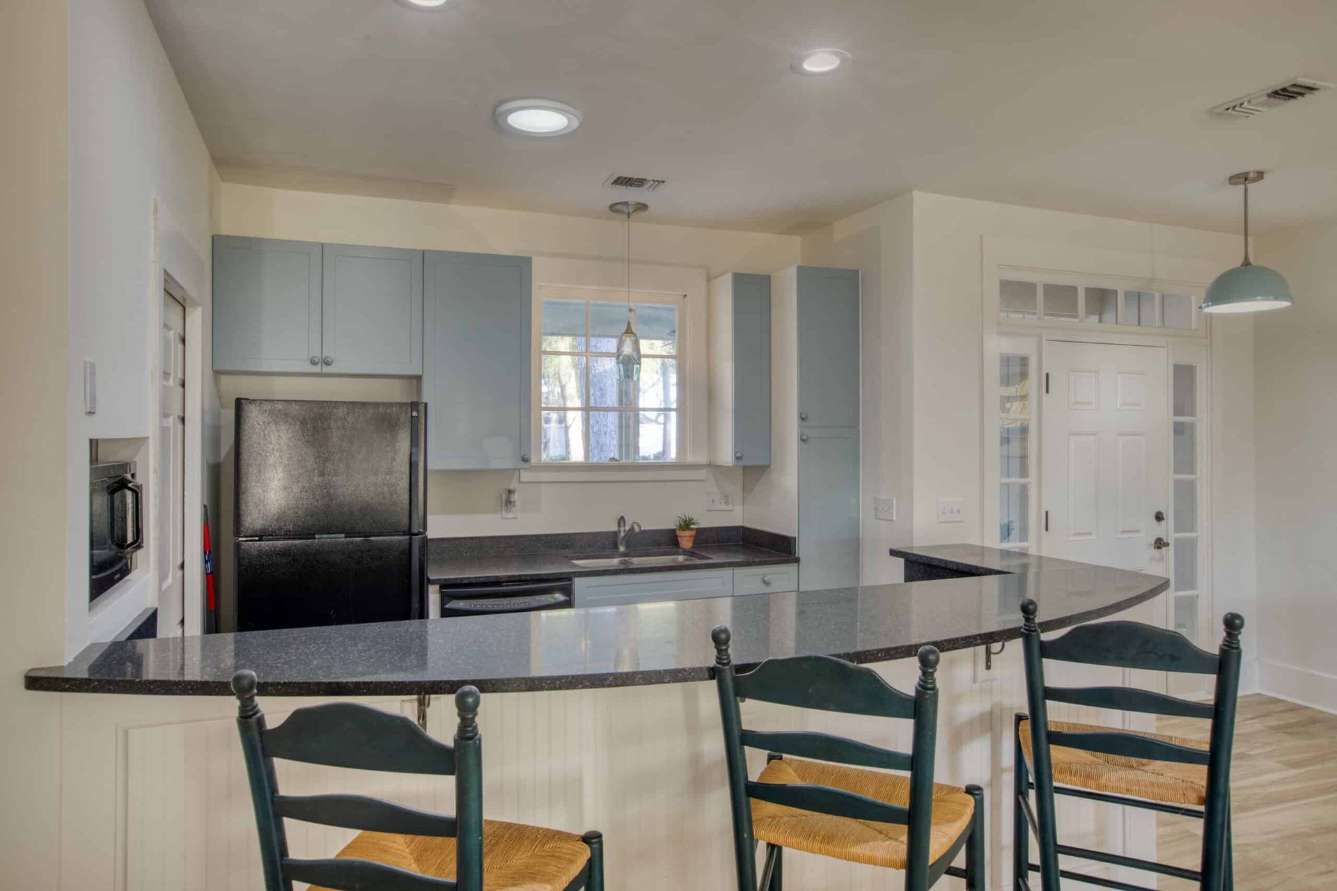 A kitchen with a refrigerator , sink , and chairs.