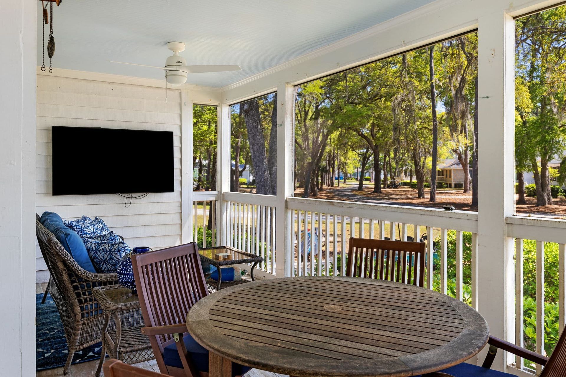 A screened in porch with a table and chairs and a flat screen tv.