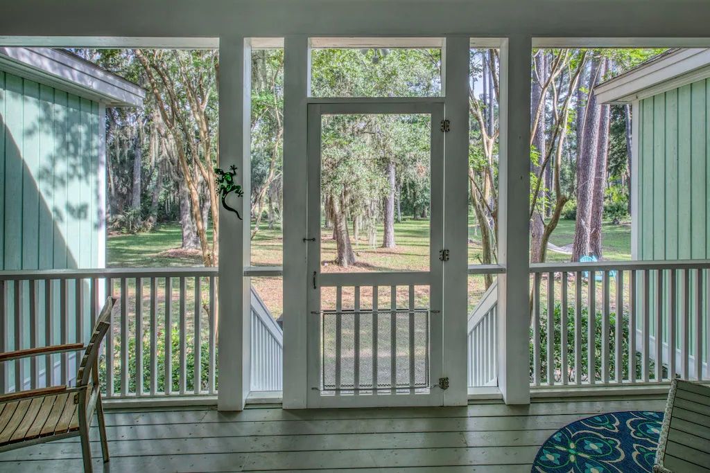 A screened in porch with a view of a forest.