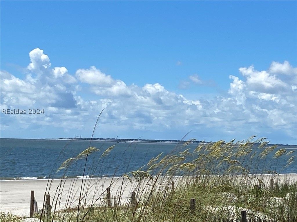 A screened in porch with white chairs and a ceiling fan.