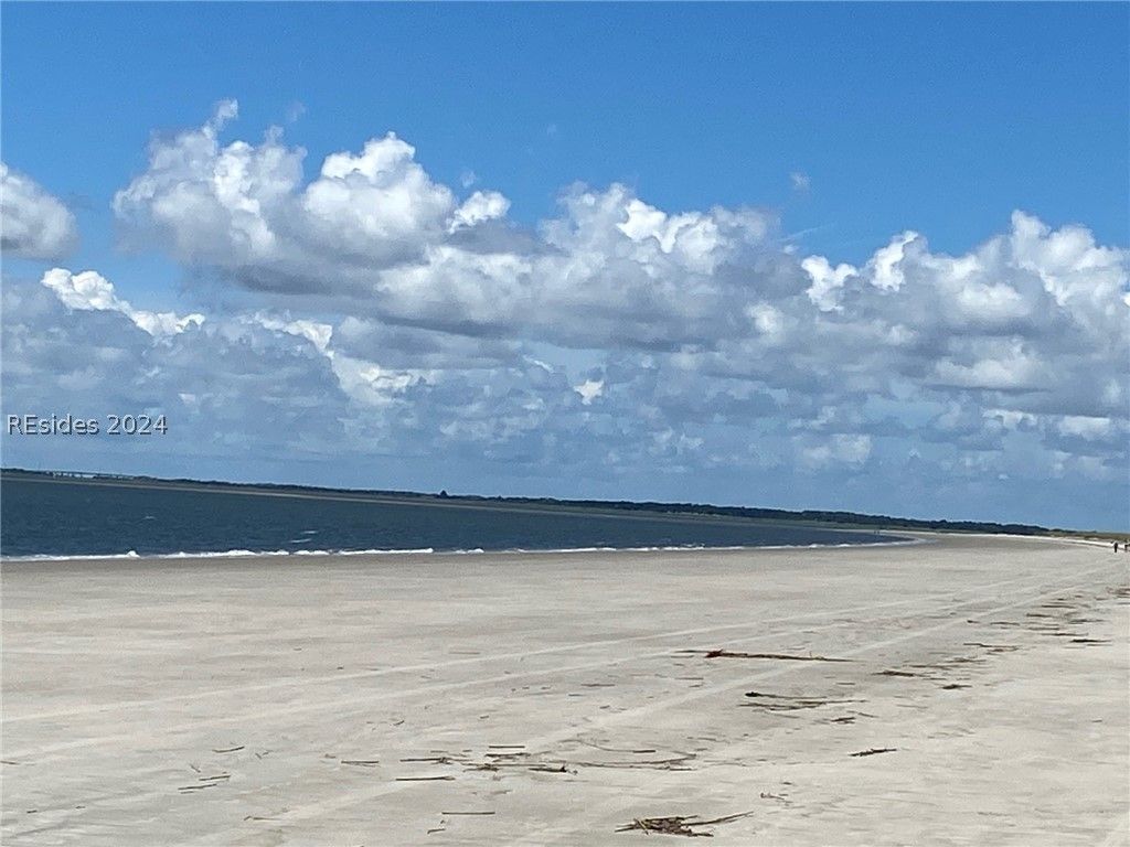 A screened in porch with a couch and chairs and a ceiling fan.