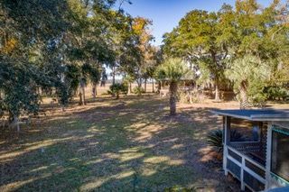An aerial view of a lush green field with trees and a house in the background.