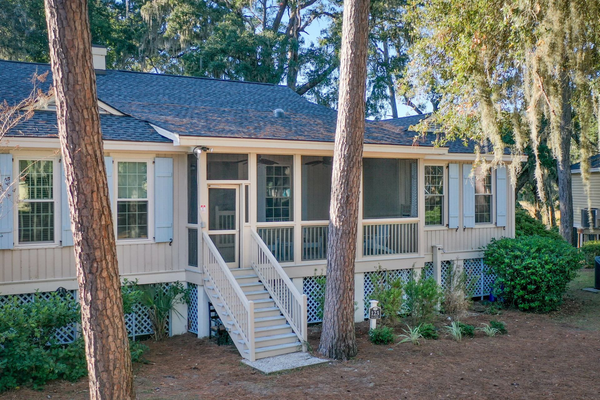 A house with a screened in porch is surrounded by trees