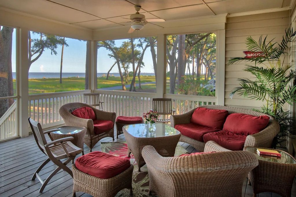A screened in porch with wicker furniture and a view of the ocean