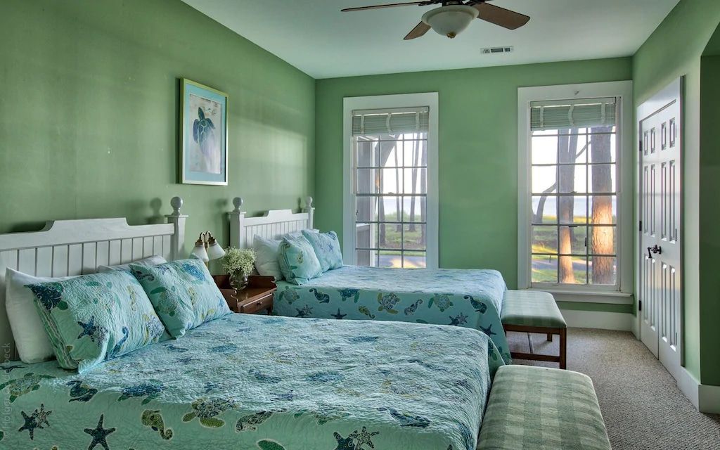 A bedroom with two beds and a ceiling fan