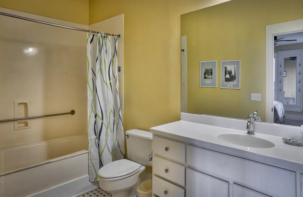A bathroom with a toilet , sink , shower and mirror.