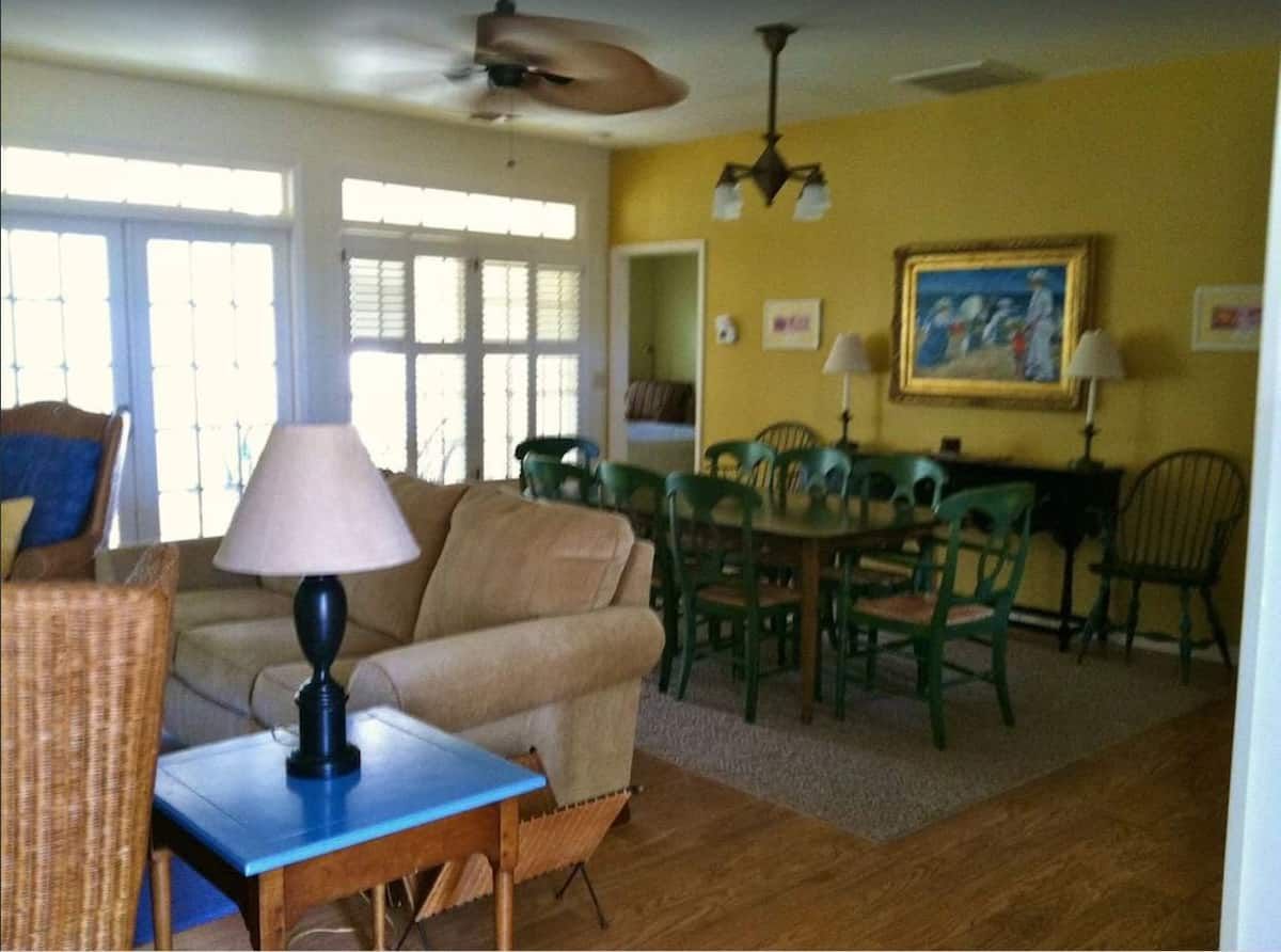 A living room with a table and chairs and a ceiling fan