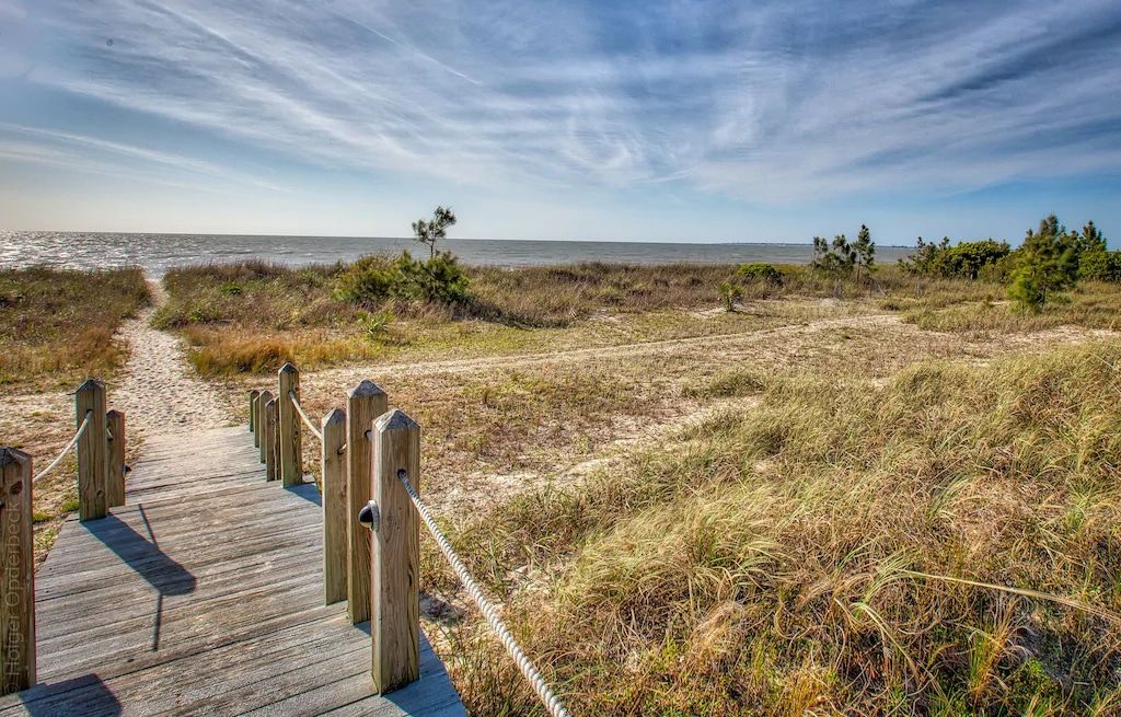 A wooden walkway leading to the beach on a sunny day.