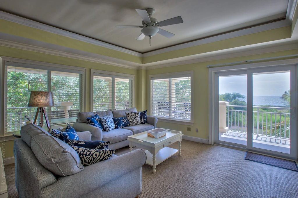 A living room with a couch , chair , coffee table and ceiling fan.